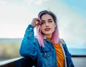 young woman with pink and purple hair looking into the distance